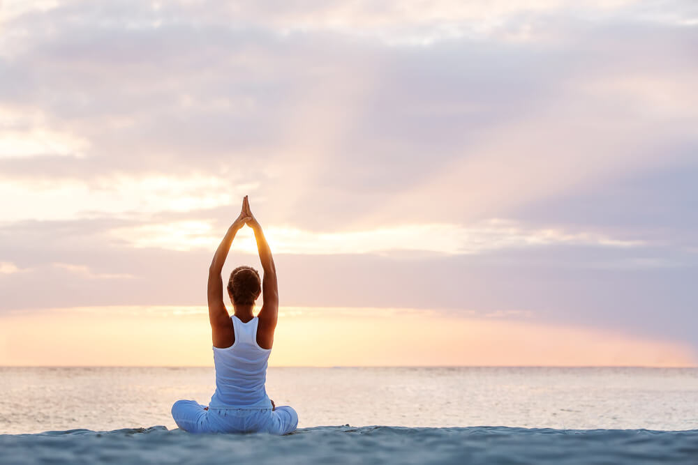 Photo of a person doing yoga on the beach during a Florida wellness retreat