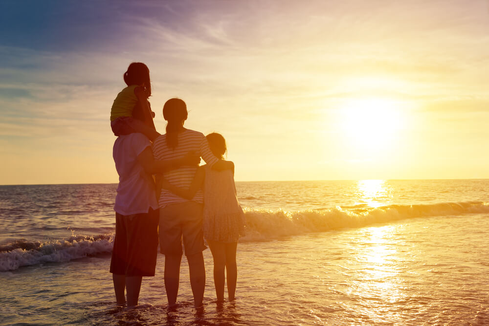 Photo of family hugging by the beach at sunset during Florida summer getaway in Indian Rocks Beach