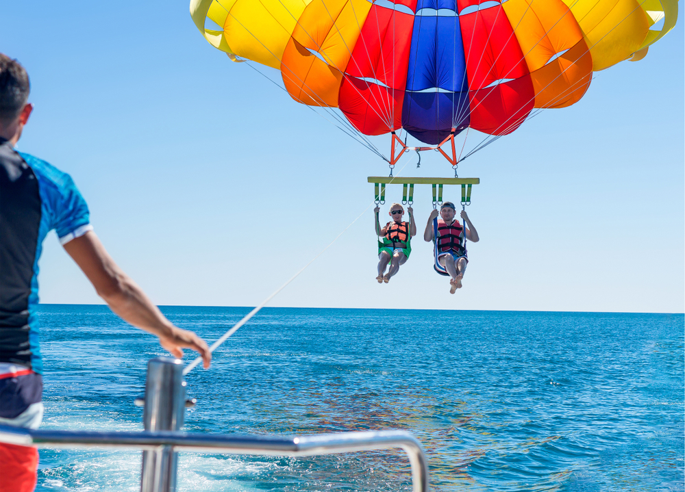 People parasailing above the water on a clear sunny day, one of the most fun activities in Florida