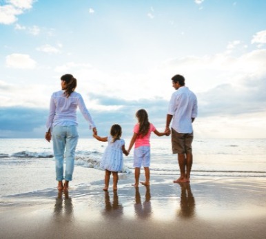 Family holding hands on beach on the water's edge | Plumlee Indian Rocks Beach Vacation Rentals