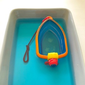 Toy boat in blue water with oil poured in | Plumlee Gulf Beach Vacation Rentals