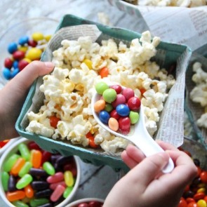 Person putting candy toppings on popcorn | Plumlee Gulf Beach Vacation Rentals