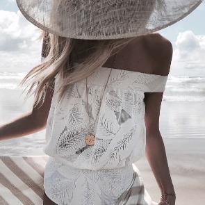 Woman on the beach wearing a big floppy beach hat with off-the shoulder swimsuit | Plumlee Vacation Rentals in Indian Rocks Beach, FL