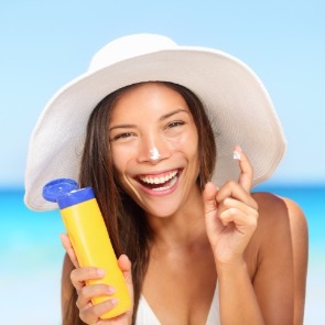 woman applying sunscreen on the beach | Plumlee Gulf Beach Realty