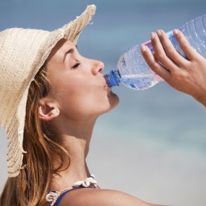 woman drinking water on the beach | Plumlee Gulf Beach Realty