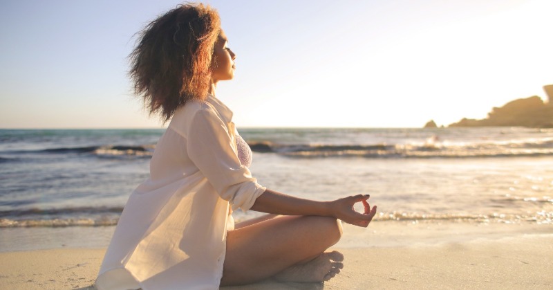 woman doing yoga on the beach | Plumlee Realty