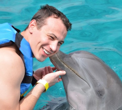 man playing with a dolphin | Plumlee Gulf Beach Realty