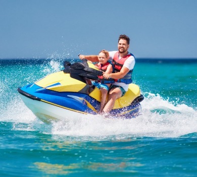 father and son riding jet ski in the ocean | Plumlee Gulf Beach Realty