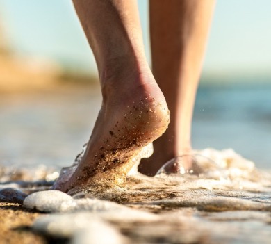 Bare, sandy feet walking through water on the beach | Plumlee Indian Rocks Beach Vacation Rentals