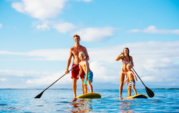 Dad and mom on paddleboards with kids | Plumlee Indian Rocks Beach Vacation Rentals