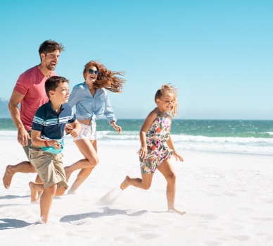 Excited family running on the beach | Plumlee Vacations Indian Rocks Beach Rentals