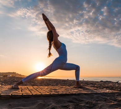 woman doing yoga on the beach | Plumlee Vacation Rentals