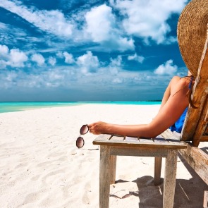 Woman sitting on a beach chair relaxing and enjoying the water views| Plumlee Indian Rocks Beach Rentals