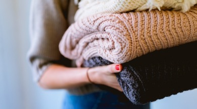 woman holding folded sweaters | Plumlee Vacation Rentals