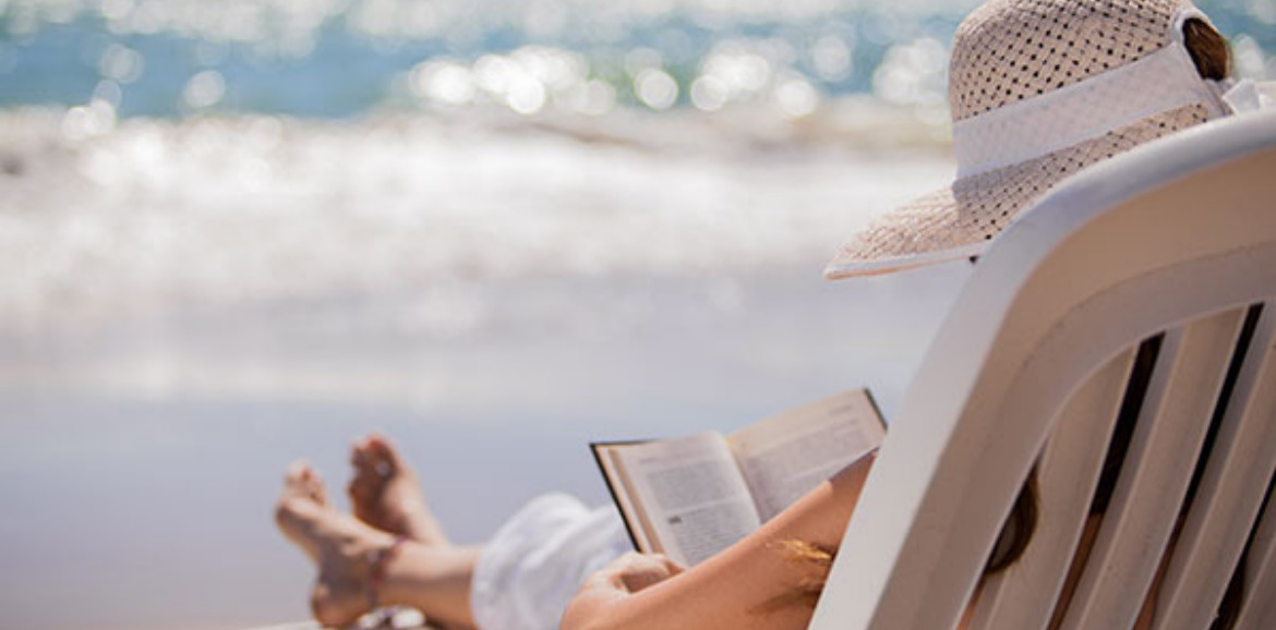 Woman reading and relaxing on the beach | Plumlee Indian Rocks Beach Rentals