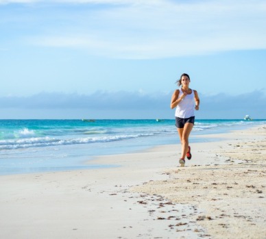 Healthy woman running on the beach | Plumlee Vacations Indian Rocks Beach Rentals